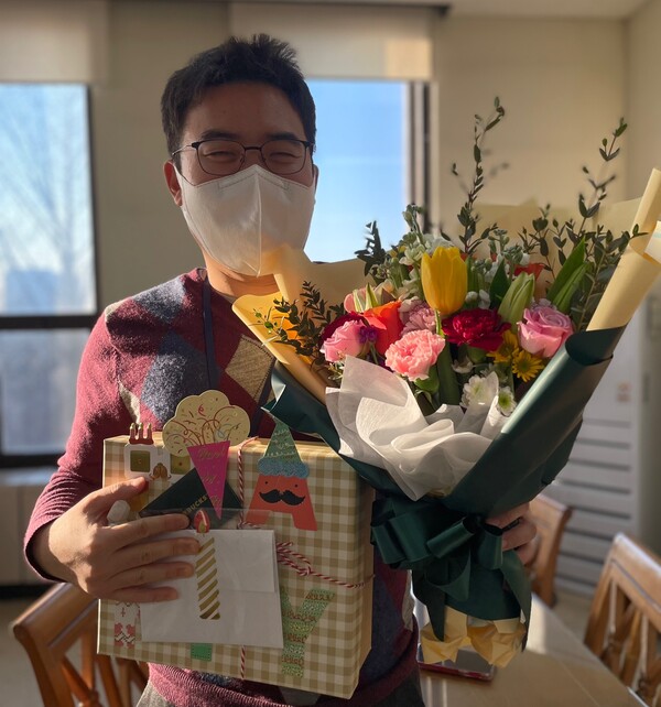 2022년 12월30일 본교에서의 마지막 근무를 기념해 동료들이 선물한 꽃다발과 선물을 들고 있는 박병현씨. 제공=박병현씨