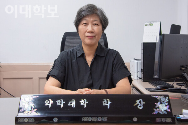 인터뷰를 마친 후, 카메라를 응시하며 미소를 짓고 있는 이화정 교수. 그의 새로운 책상 한 켠에는 과거 제자가 보낸 축하 화환이 놓여있다. <strong>강연수 사진기자