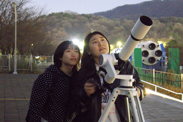 천체망원경을 사용할 때는 2인 1조를 이뤄 서로 망원경을 잡아주고, 별에 관한 이야기를 나누기도 한다. 김다은(경영·25)씨(왼쪽)와 장윤정(호크마·25)씨가 함께 밤하늘을 올려다보고 있다. <strong>정영인 사진기자