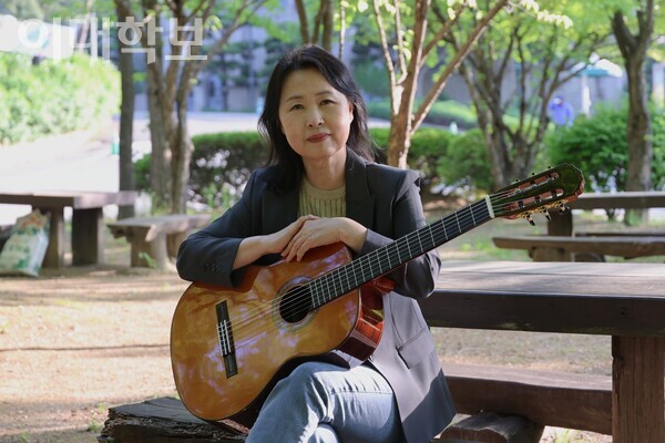 학문관 벤치에 앉아 기타를 무릎에 올려 보이는 신경숙 회장. 진유경 사진기자