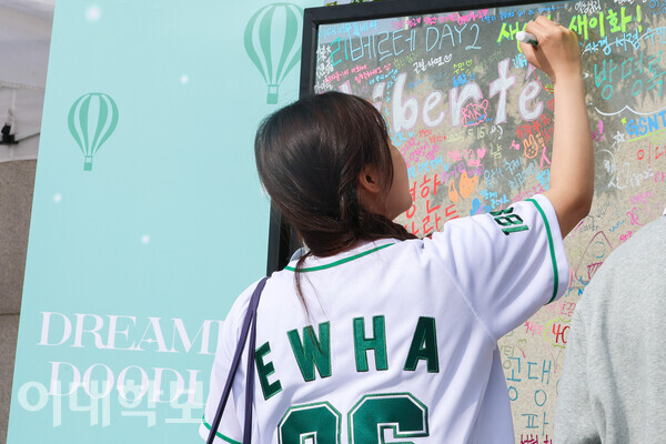 정문 앞 축제준비위원회가 주관하는 행사에 참여한 이화인이 방명록을 남기고 있다. <strong>진유경 사진기자