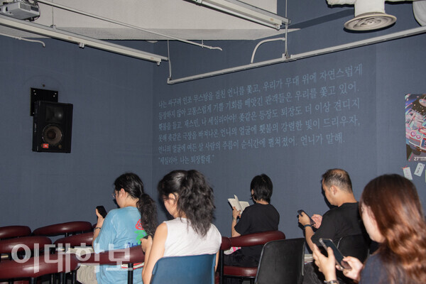 이화 시네마떼끄에서 개막작 ‘퇴장하는 등장 1’(2025)의 무대를 기다리는 관람객들의 모습. 극의 한 대사가 벽에 영사되고 있다. 변하영 사진기자