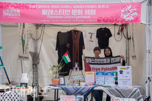 13일 진행된 2025 신촌글로벌대학문화축제의 ‘팔레스타인 문화 체험’ 부스. 부스 운영에 참여한 우리대학 인티파다 동아리원들이 “팔레스타인인들과 연대를!”이라고 써진 깃발을 들며 웃어 보이고 있다. 진유경 사진기자