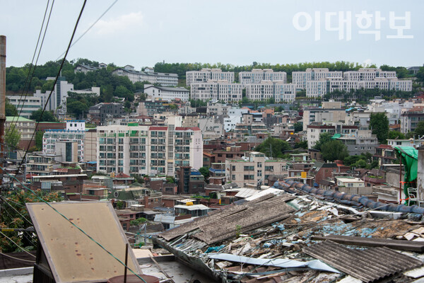 북아현동 달동네 위쪽에서 바라본 마을의 전경. 헌 판자가 덮은 집과 오래된 주택들이 모여있고, 그 너머로는 우리대학 기숙사 건물이 늘어서 있다. <strong>진유경 사진기자