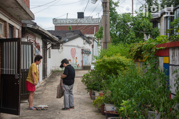 북아현로 4차길의 모습. 한 아주머니가 계란을 사들고 지인의 집을 방문해 이야기를 나누고 있다. <strong>진유경 사진기자