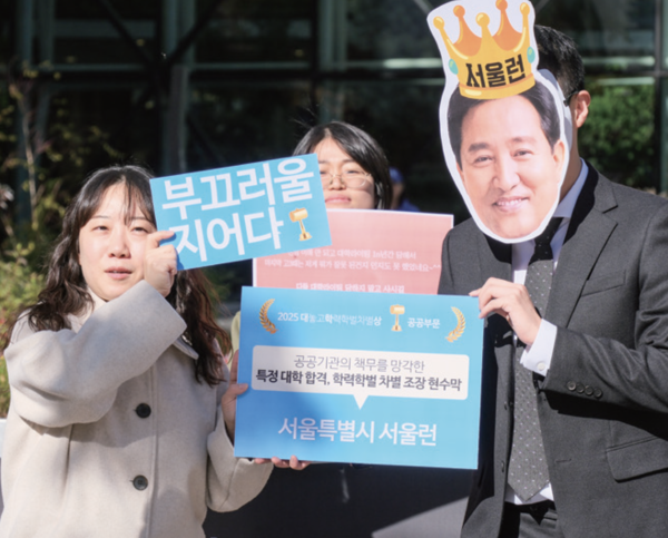 난다씨가 오세훈 서울시장의 가면을 쓴 사람에게 ‘대놓고학력학벌차별상’을 수여하며 학벌주의를 조장한 서울특별시의 ‘서울런’ 프로그램을 풍자하고 있다. 제공=투명가방끈